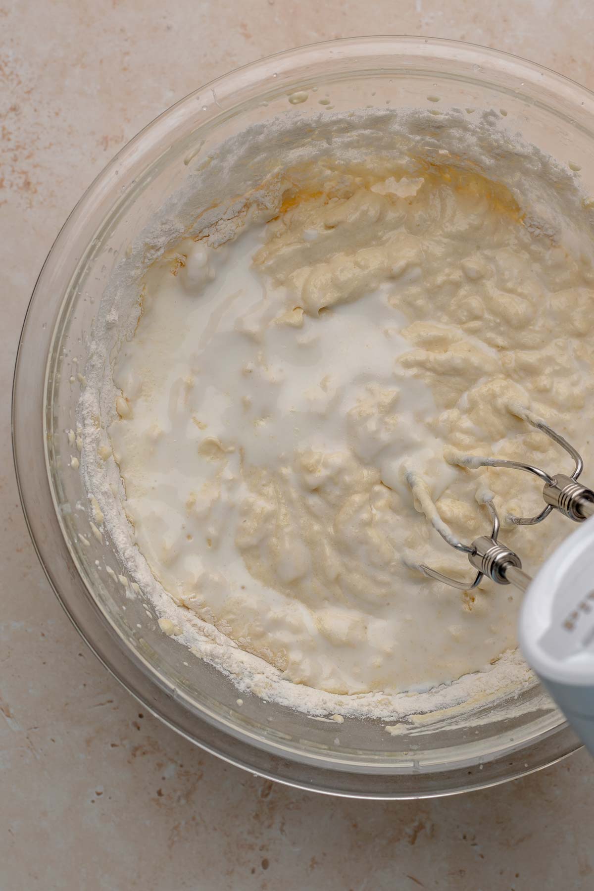 A hand mixer beats buttermilk into cupcake batter.