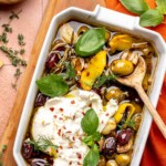 Roasted olives and burrata in a baking dish.