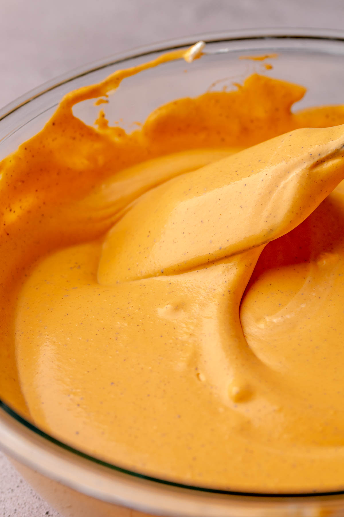 A spatula folds smooth ice cream in a bowl.