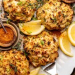 Crab stuffed portobello mushrooms on a platter with old bay and lemons.