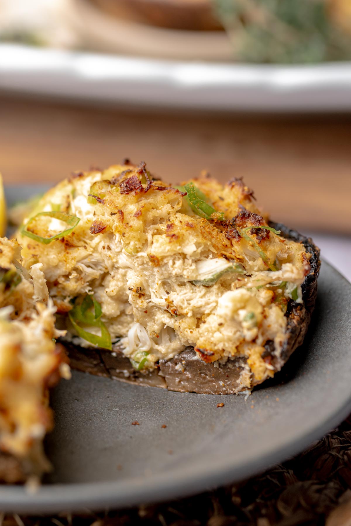 A portobello mushroom stuffed with crab meat cut in half on a plate.