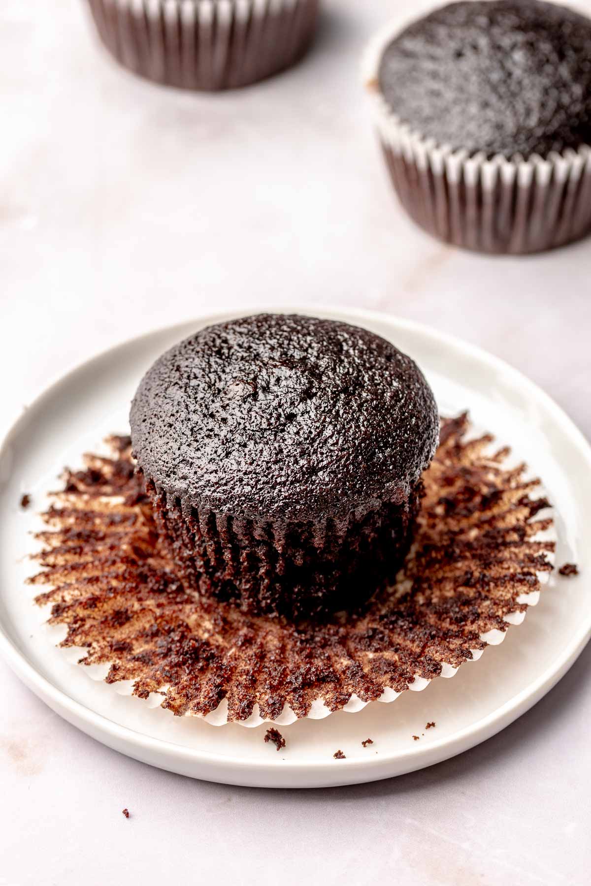 Chocolate cupcake unwrapped on a plate.