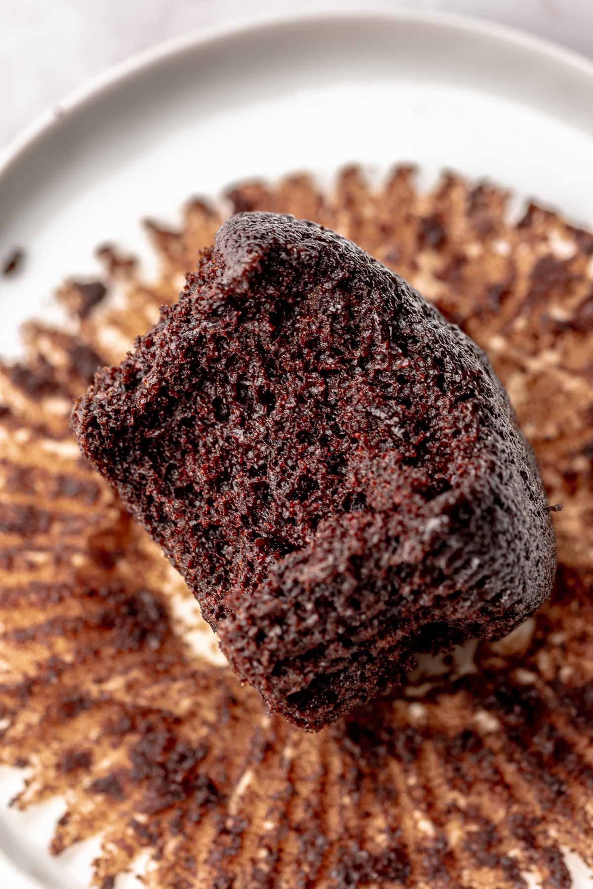 Chocolate cupcake on a plate with a bite removed.