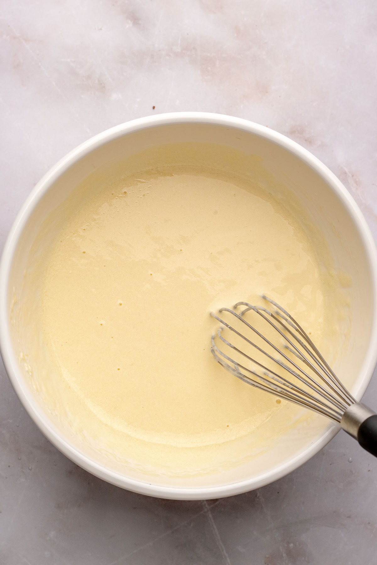 A hand whisks wet ingredients in a bowl.