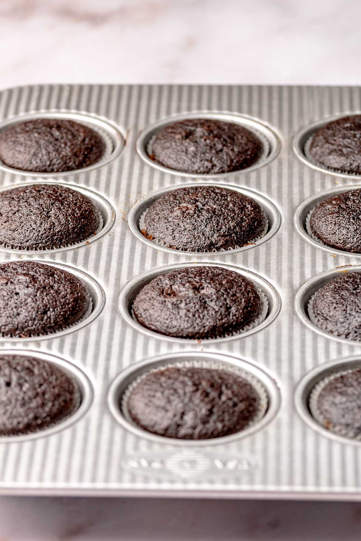 Baked chocolate cupcakes in a muffin tin.