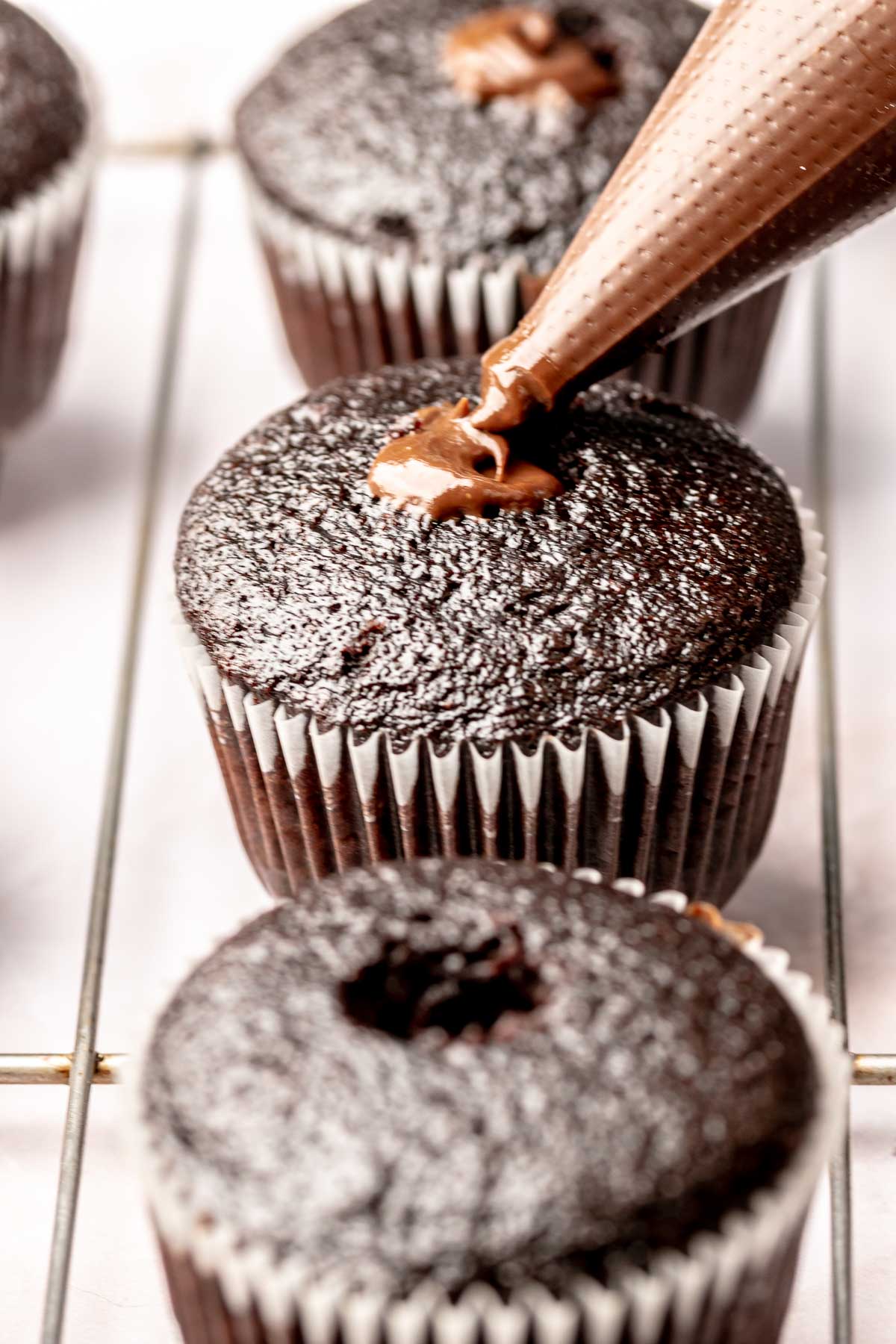 Chocolate cupcakes being filled with chocolate ganache.