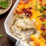 A spoon scoops out a spoonful of chicken bacon ranch dip from the corner of a casserole dish.