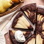 Sliced chocolate pear cake. One slice has a dollop of whipped cream on it.