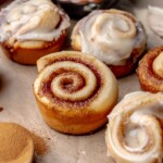 An array of mini cinnamon rolls, half are frosted.