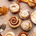 An array of mini cinnamon rolls, half are frosted.