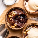 A spoon sits in a ramekin of chocolate lava cake with a bite removed.