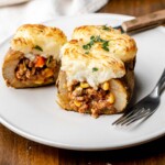 Stuffed potato cut open on a plate with a fork on it.