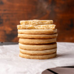 A stack of round shortbread cutout cookies. The two top ones are broken in half.