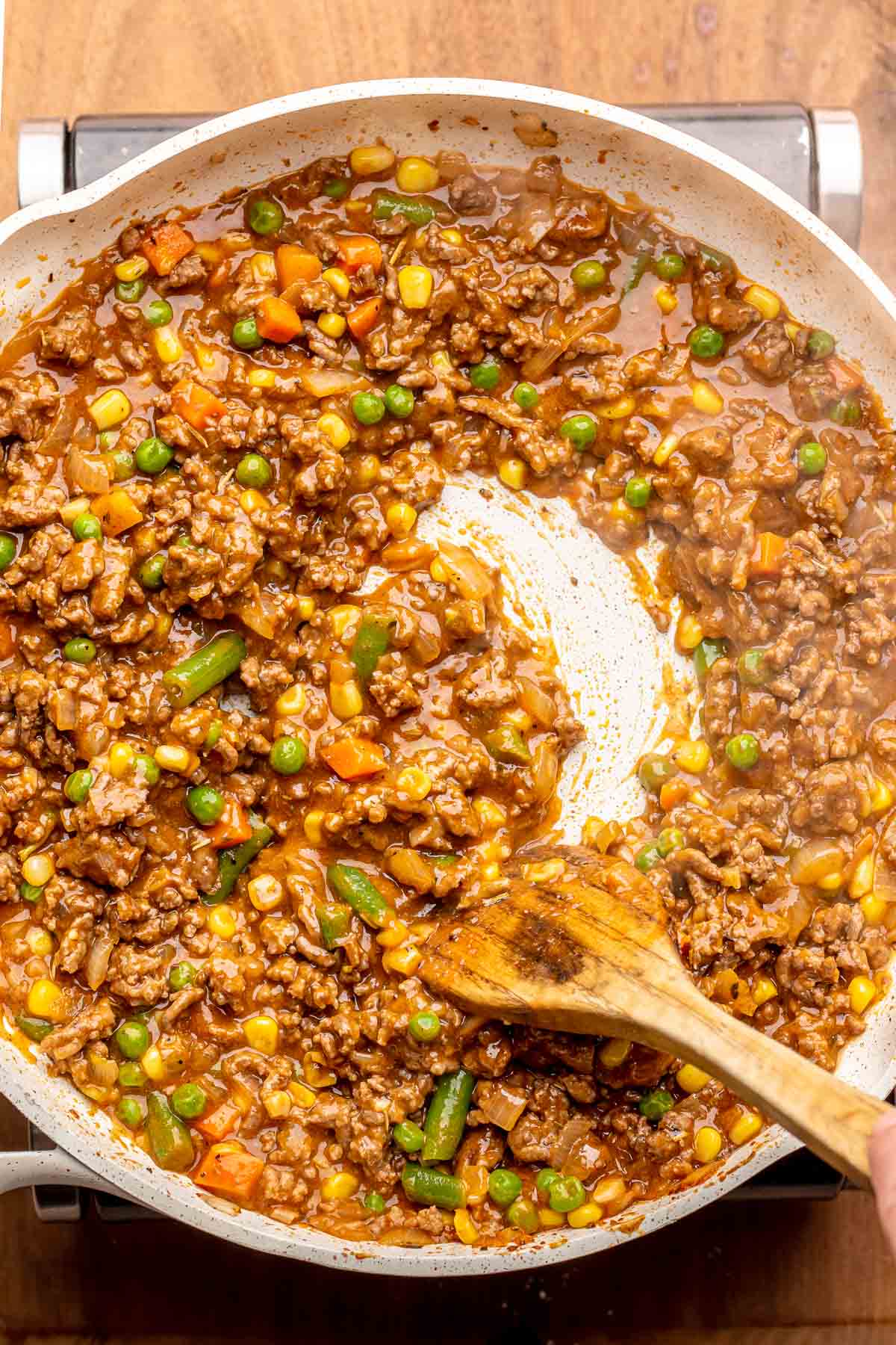 A spoon stirs shepard's pie filling in a pan.