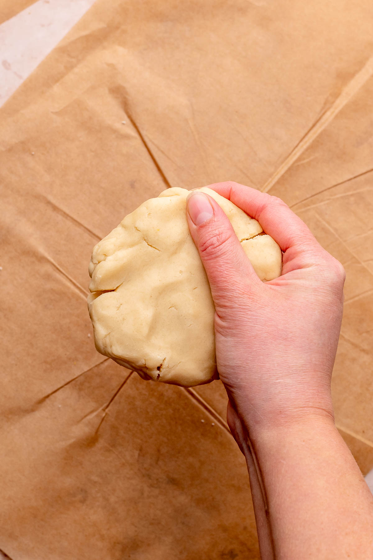 A hand squeezes cookie dough together.