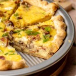 Sliced bacon mushroom quiche in a pie plate.