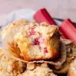 Rhubarb muffin with a bite removed in a basket of other muffins.