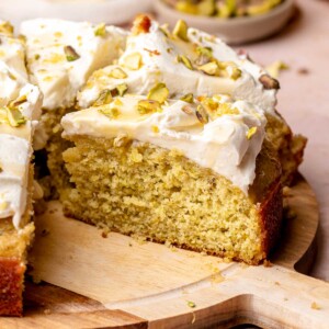 Sliced lemon pistachio cake on a wooden board.