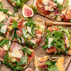 Sliced fig and prosciutto flatbread on a cutting board.