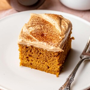 A square slice of pumpkin spice latte cake on a plate with a fork.
