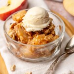 Toffee apple hazelnut crumble in a bowl with ice cream on top.