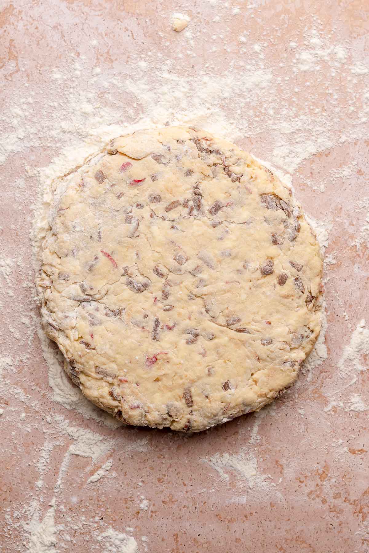 Cinnamon scone dough patted into a circle on a counter.
