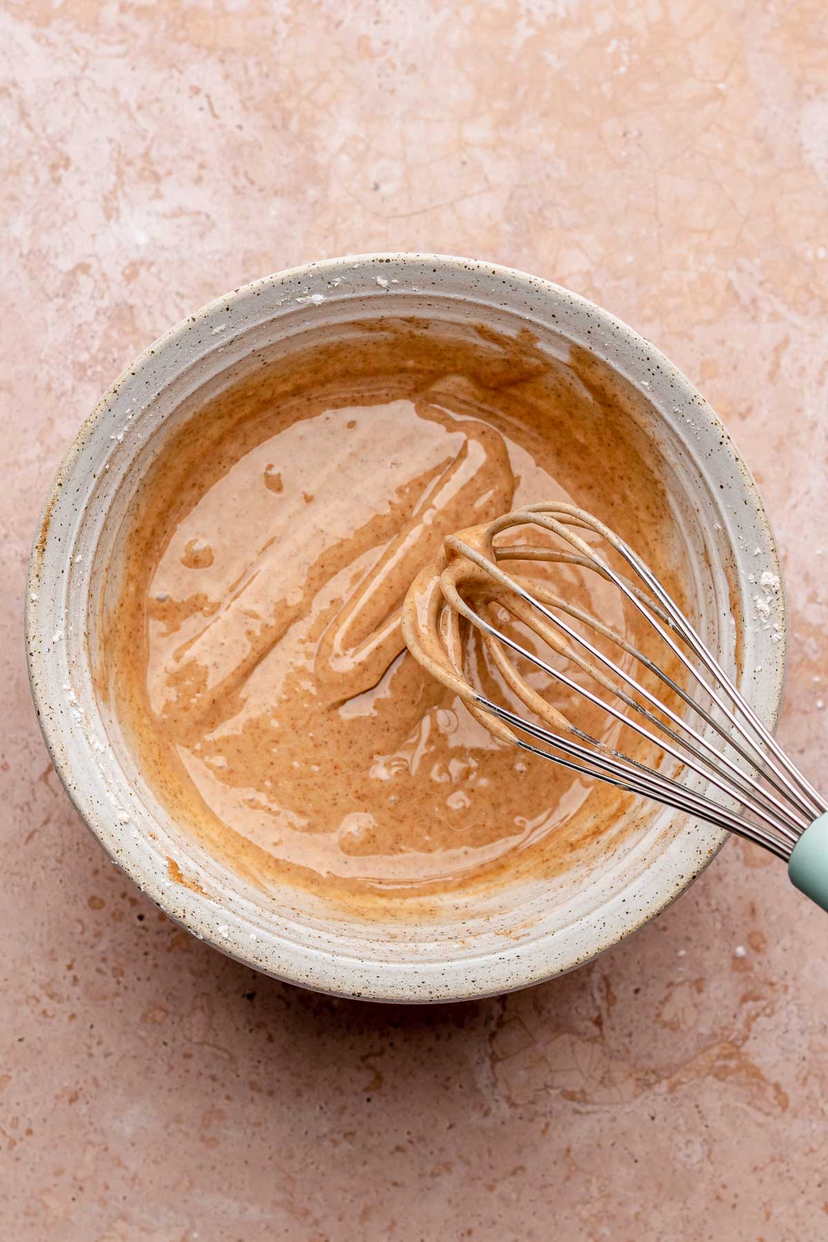 Cinnamon glaze in a bowl with a whisk.