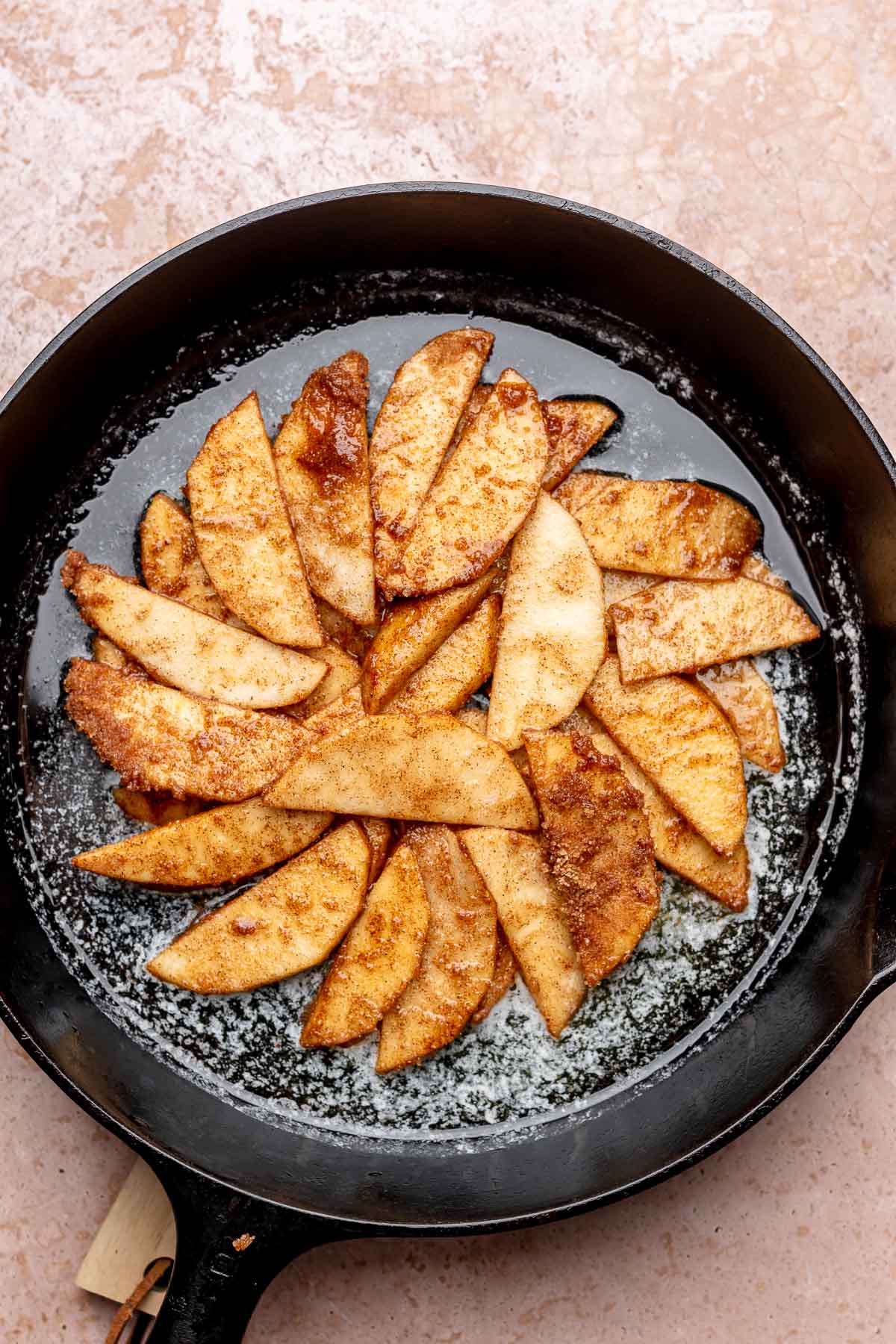 Apple slices arranged in the middle of a cast iron pan in a fan pattern.