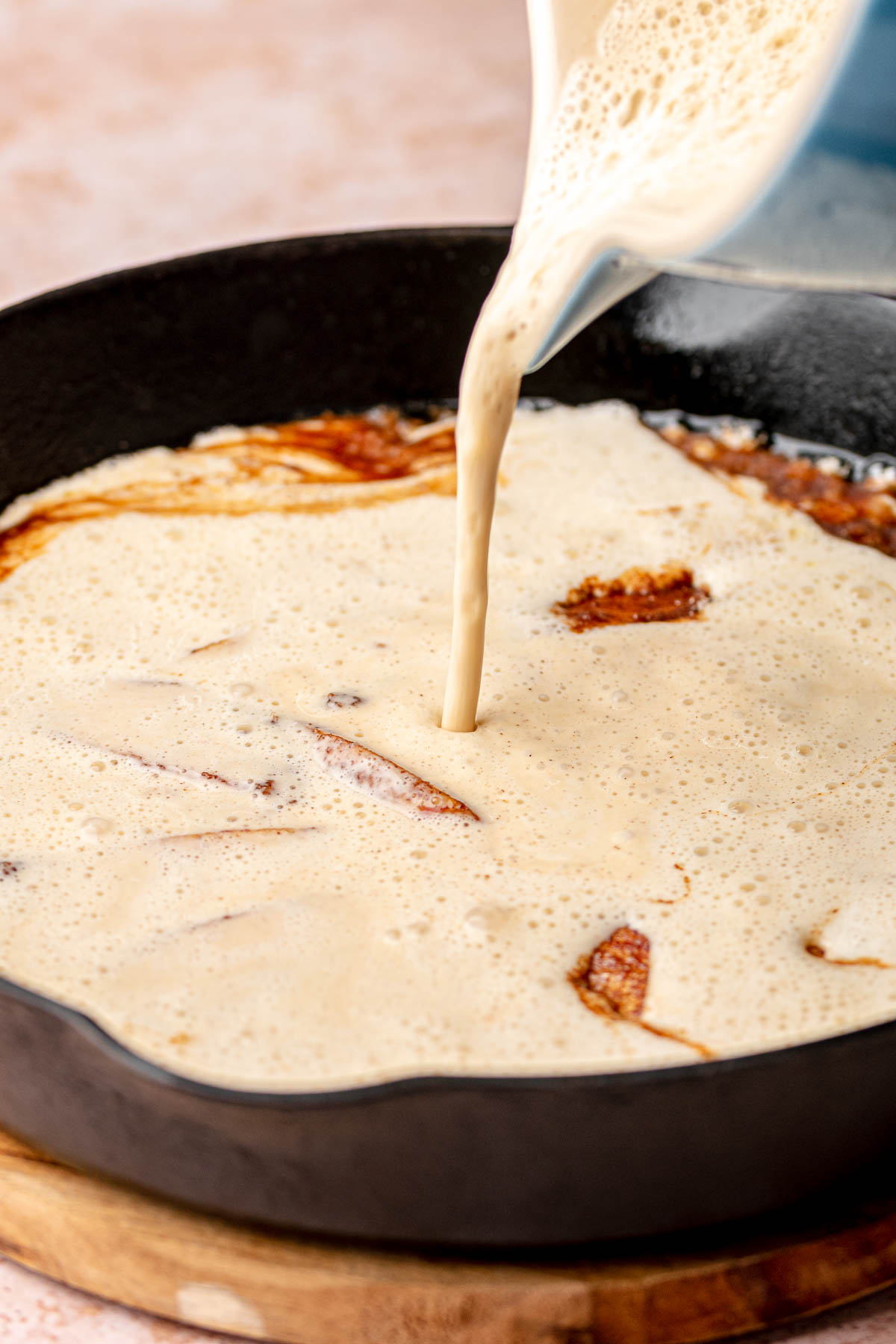 Batter pouring onto the cinnamon sugar apples in a pan.