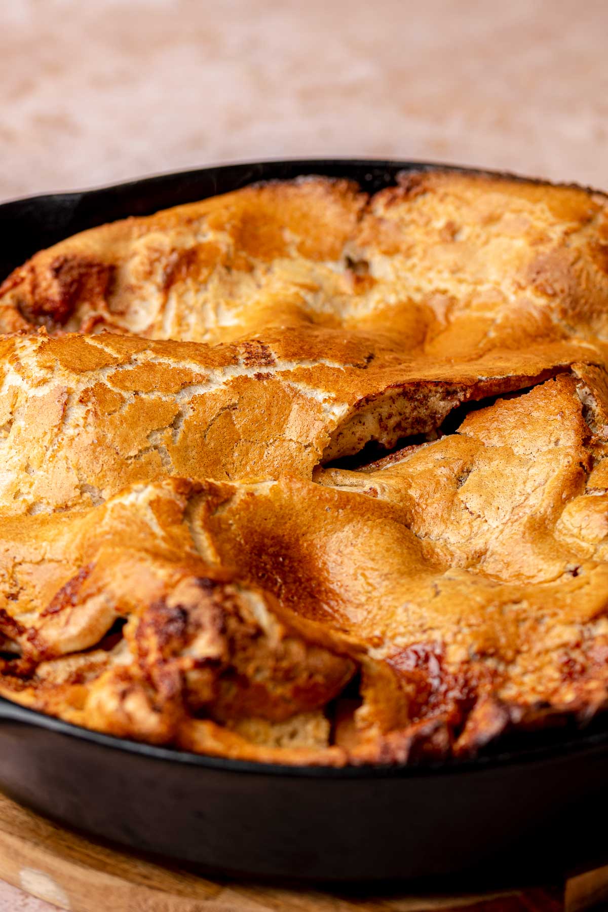 Baked, puffy cinnamon apple dutch baby in a cast iron pan.