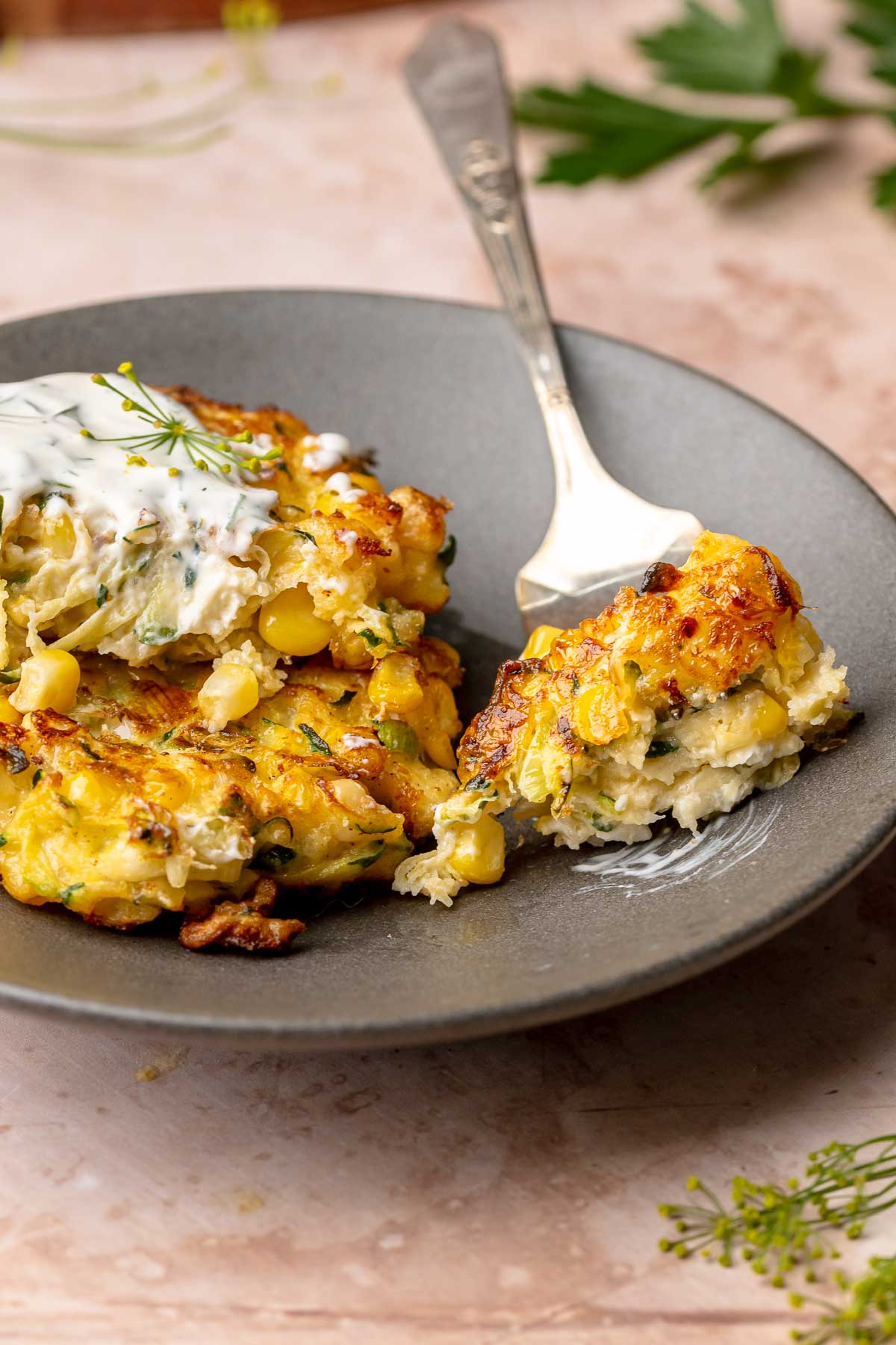 A fork holds a piece of fritter on a plate.