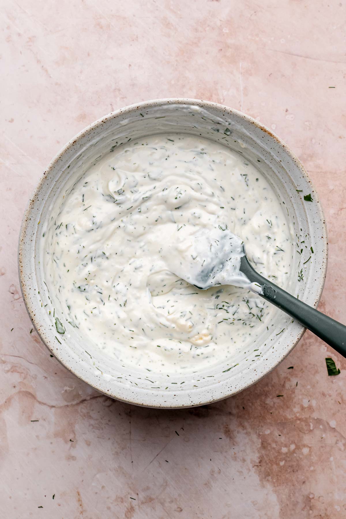 Herb yogurt sauce in a bowl with a spatula.