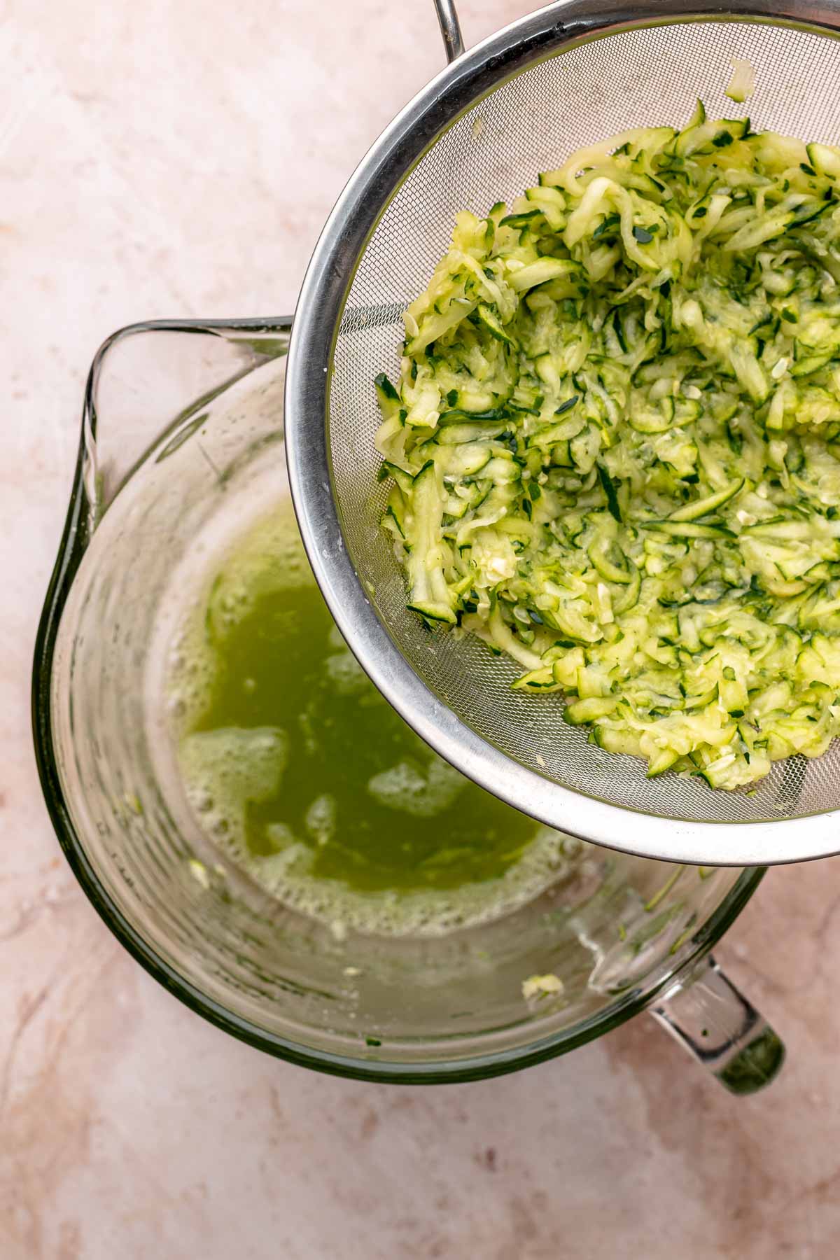 Zucchini and its juice in a colander and bowl..