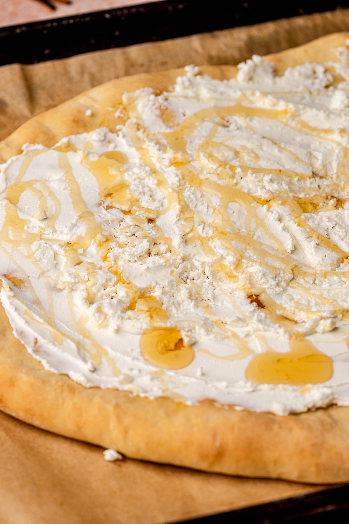 Goat cheese and honey spread onto a piece of flatbread.