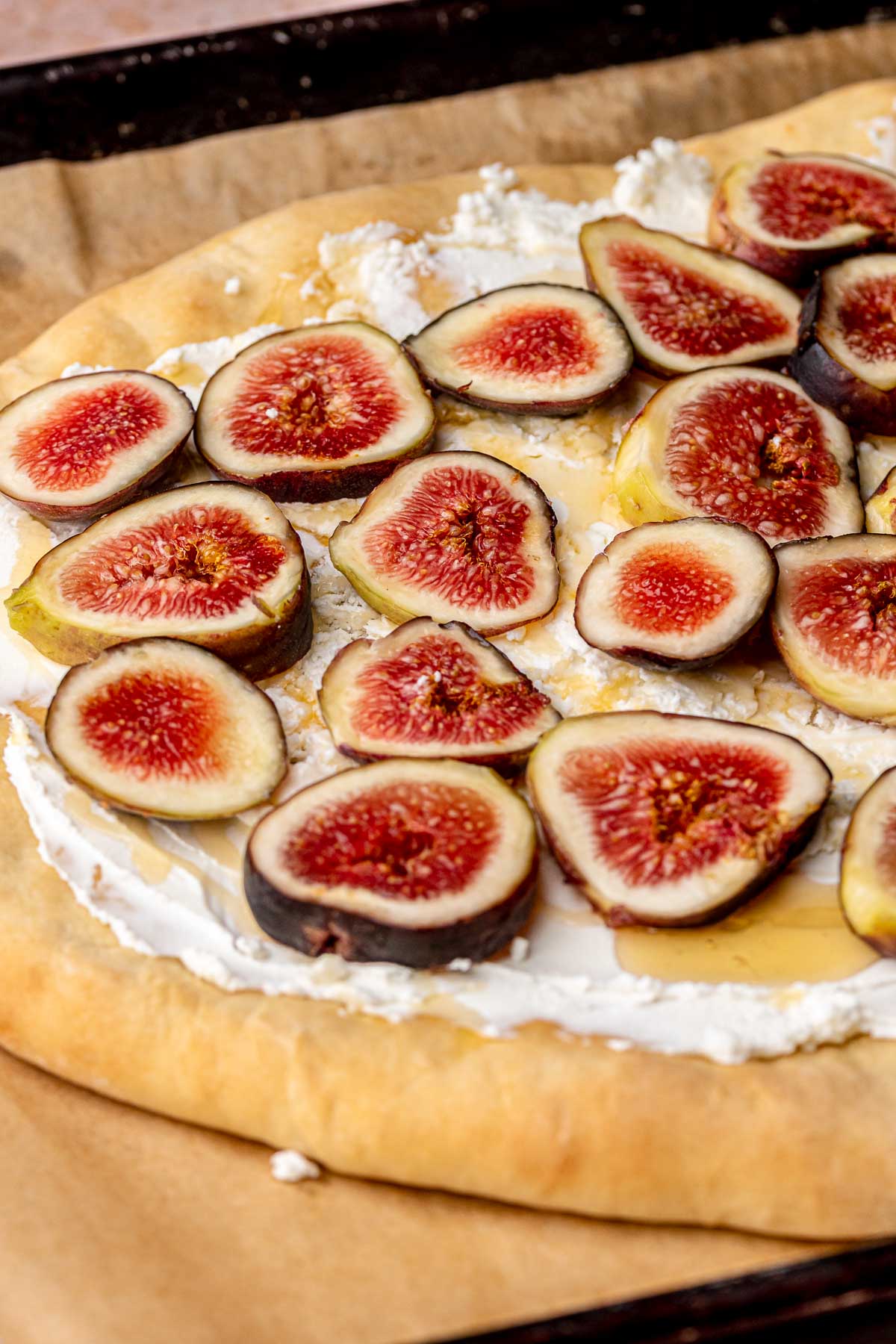 Sliced figs added on top of goat cheese flatbread.