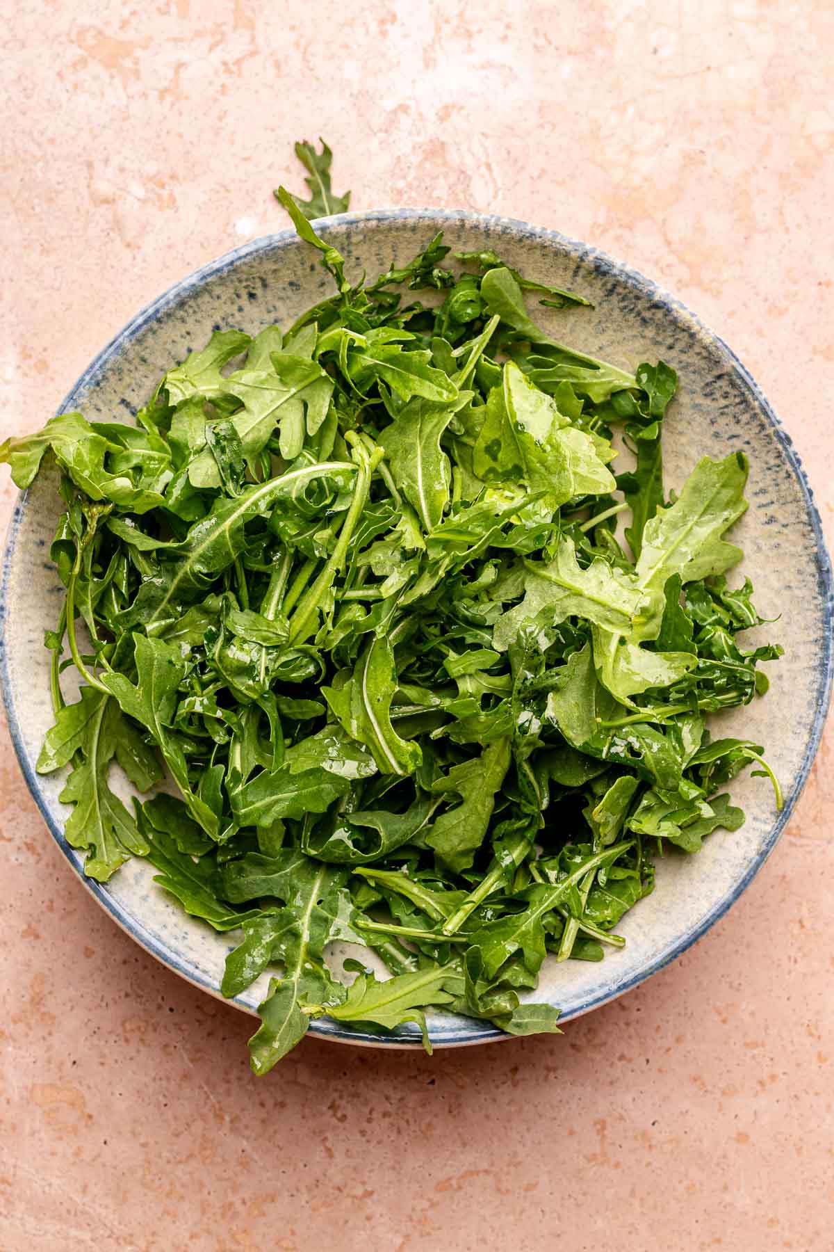 Arugula in a bowl dressed with oil and lemon.