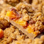 A slice of peach crumble bars sliced laying on its side.