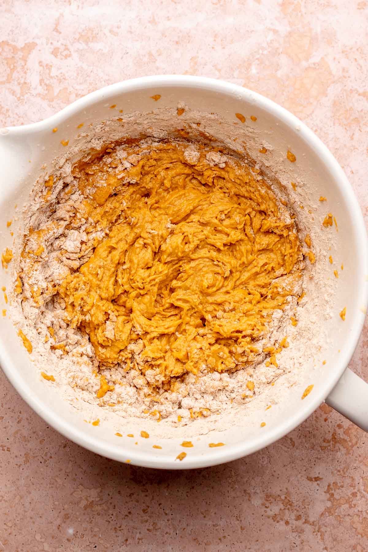 Half milked pumpkin cake batter in a bowl.