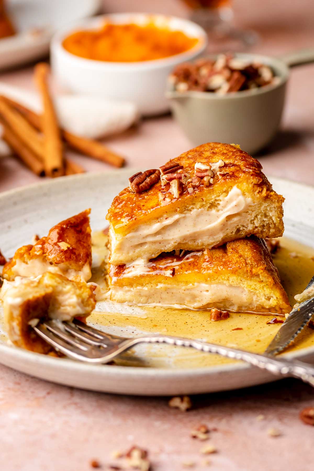 Stacks of pumpkin stuffed french toast on a plate. A fork holds a piece.