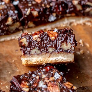 A piece of chocolate pecan pie bar laying on its side.