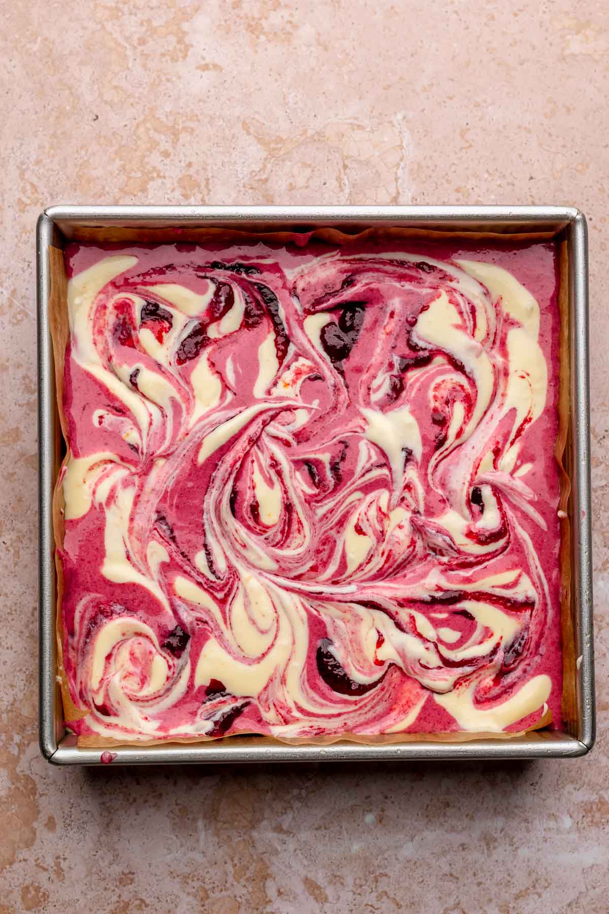 Swirled cranberry and vanilla batters in a square pan.