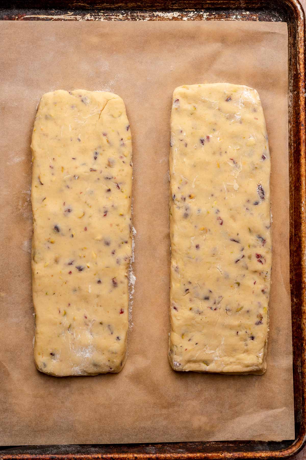 Two planks of pistachio biscotti dough formed on a sheet pan.