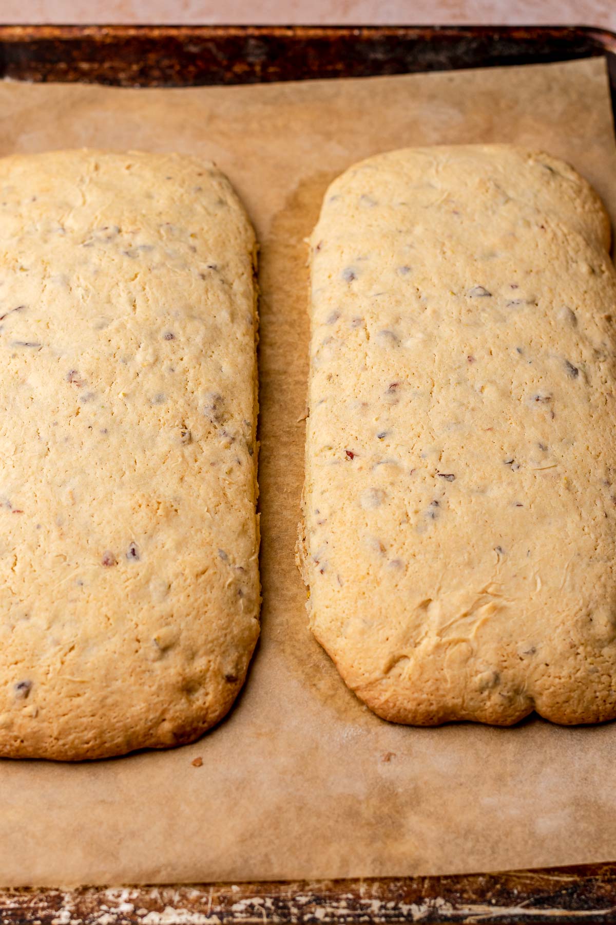 Two planks of baked biscotti mounds on a sheet pan.