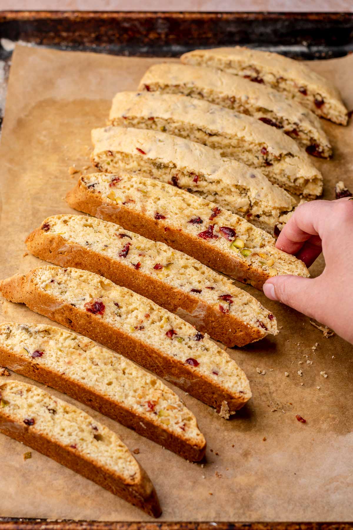 A hand turns over pieces of biscotti onto their sides.