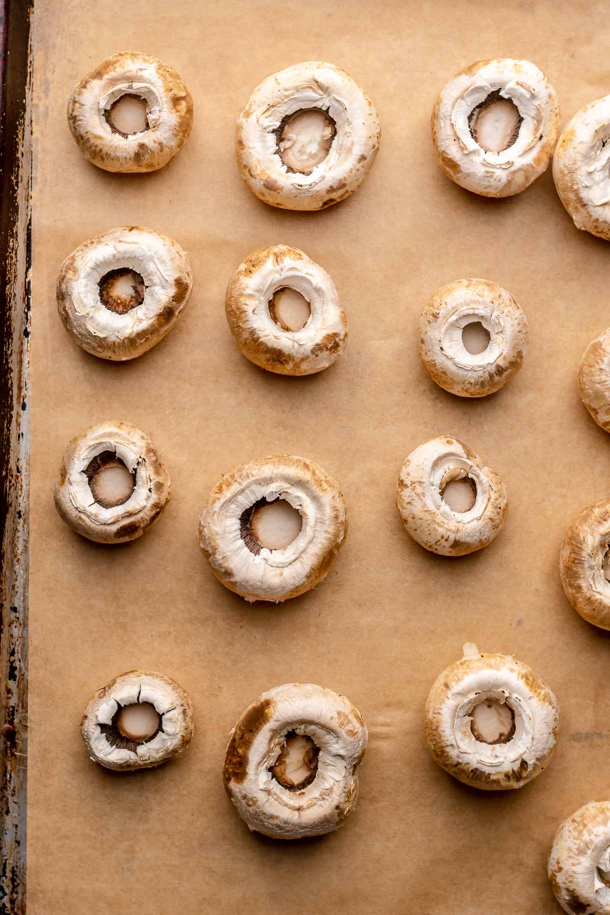 Mushroom caps on a sheet pan with stems remoed.