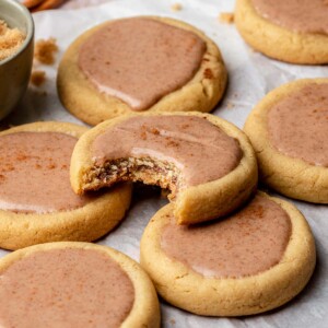Finished brown sugar pop tart cookies on parchment paper. One has a bite removed.