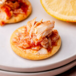 Crab cocktail dip on a cracker sitting on a plate.