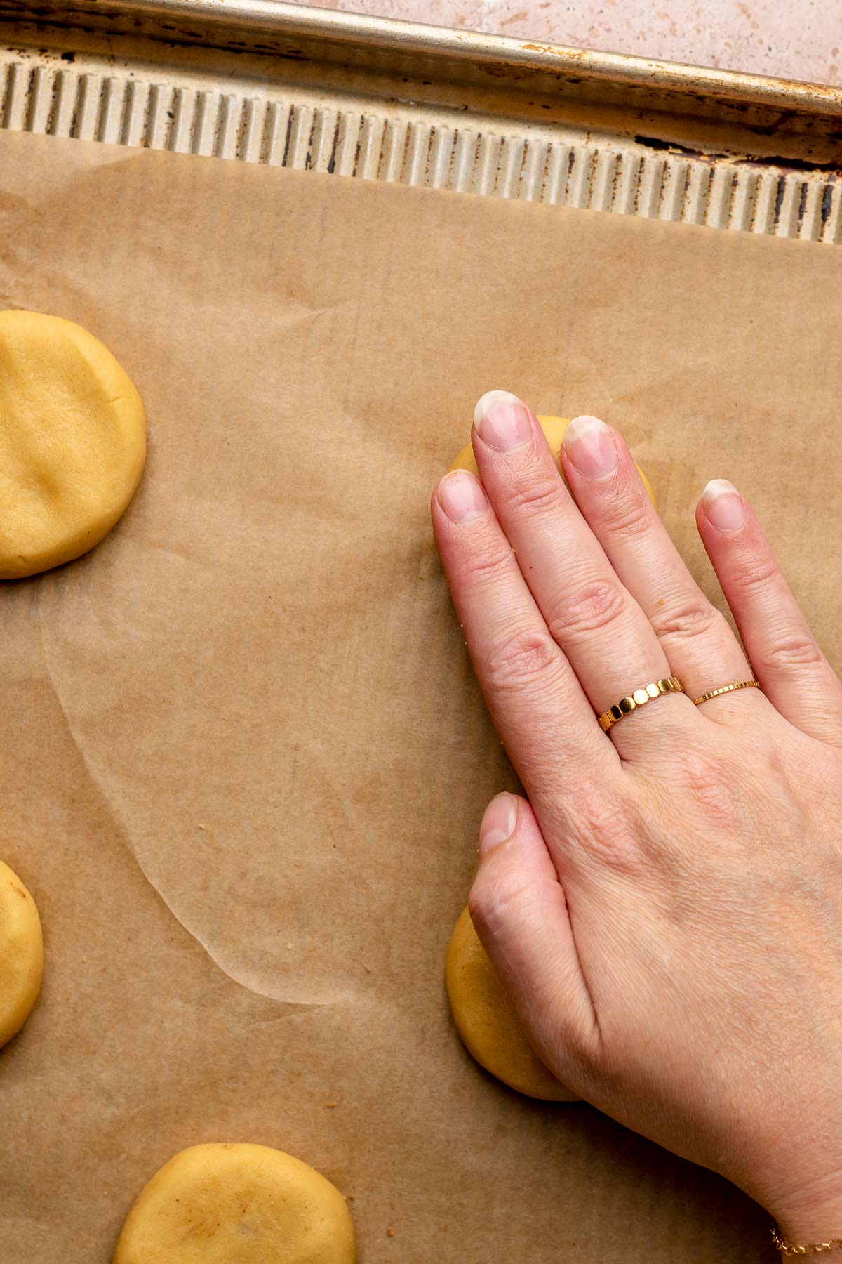 A hand bpresses down on filled cookies to flatten them.