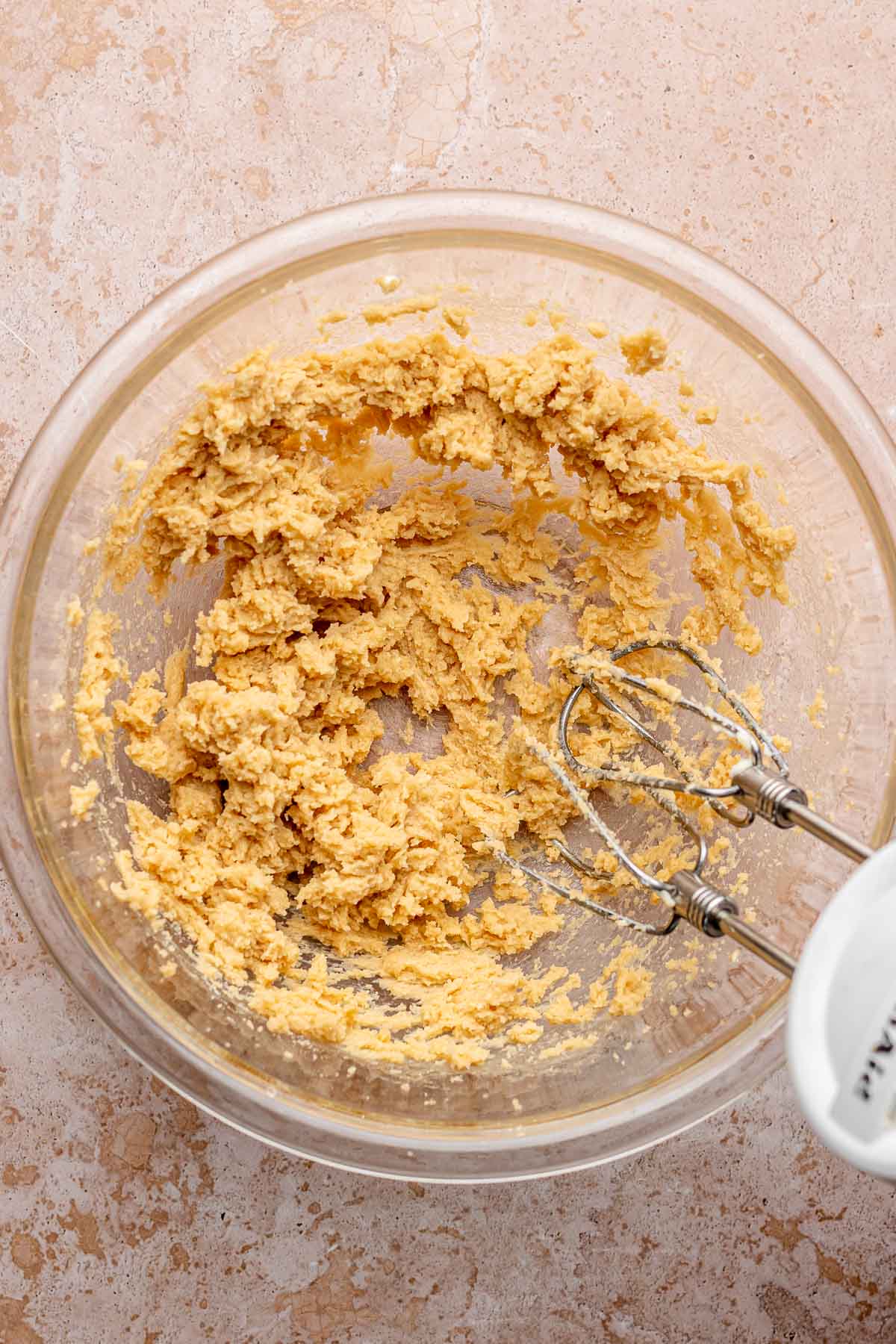 A hand mixer mixes cookie dough in a bowl.