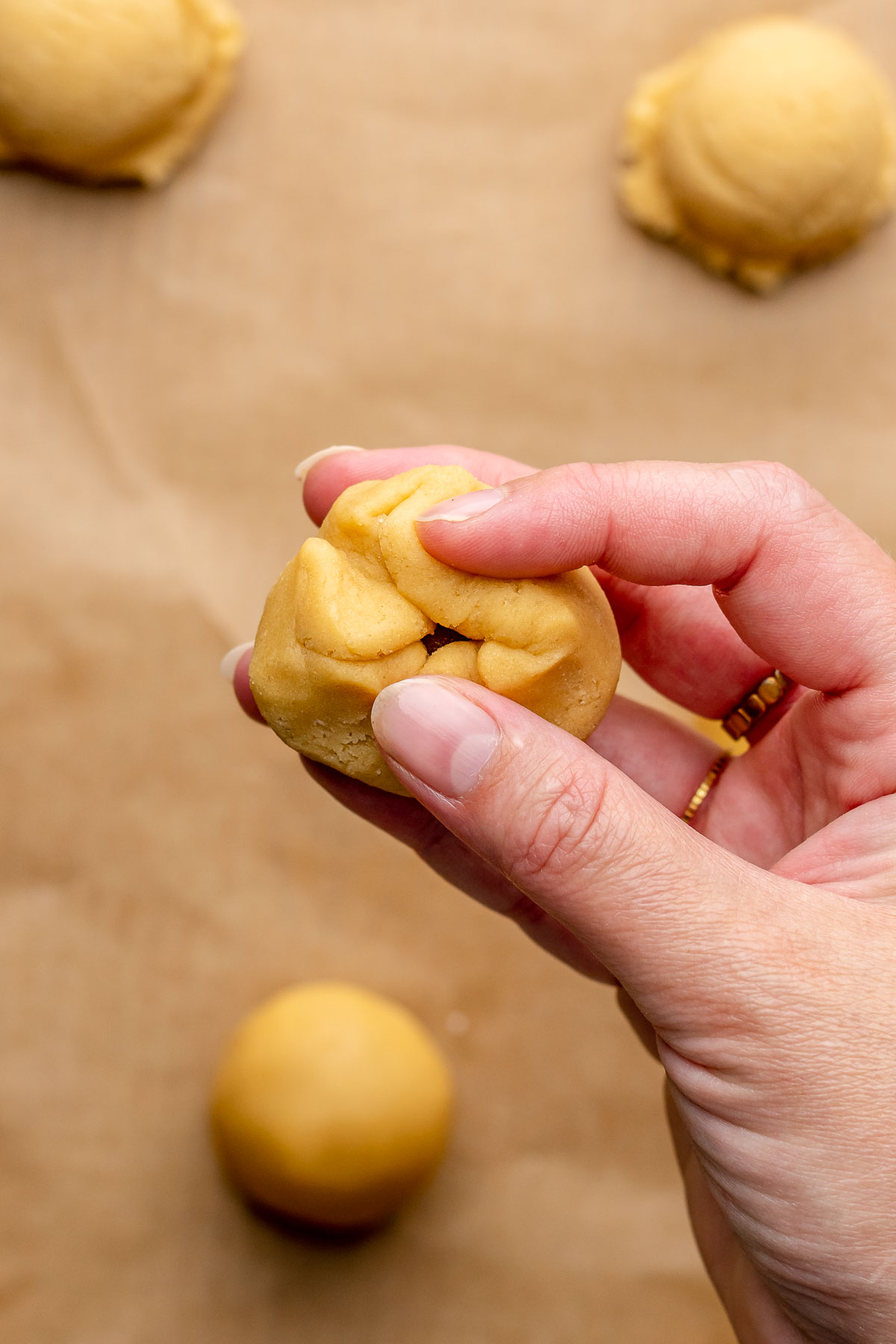 A hand closes dough around a dollop of cinnamon sugar.